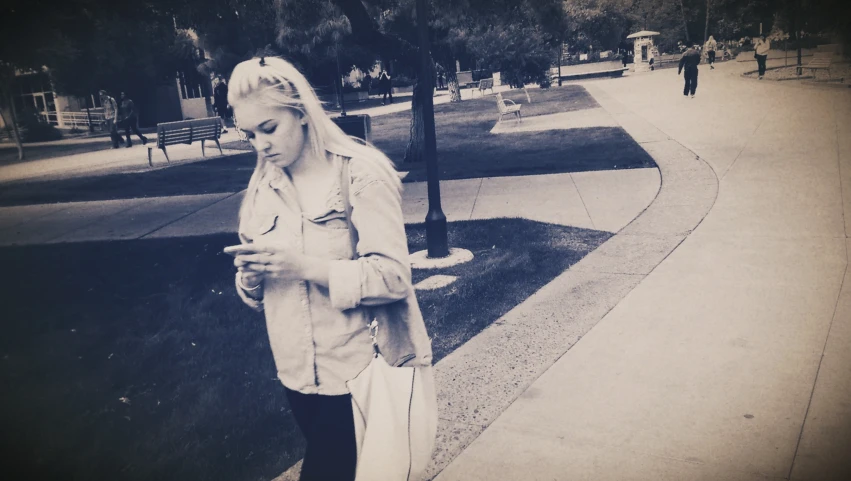 a woman is standing with her cellphone at the park