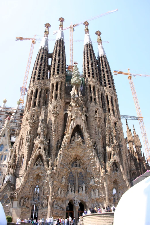 the huge cathedral has many spires and construction cranes behind it
