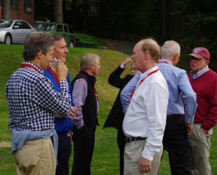 a group of men standing in a yard talking