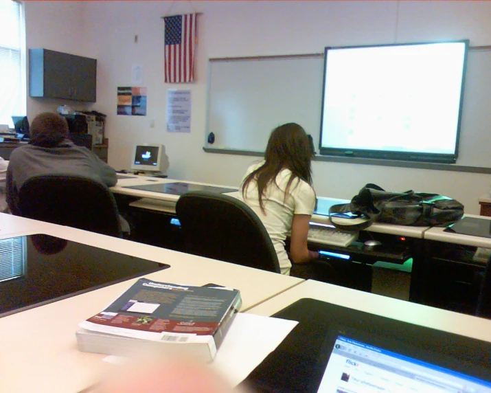 some people at desks with two monitors and one woman using a computer