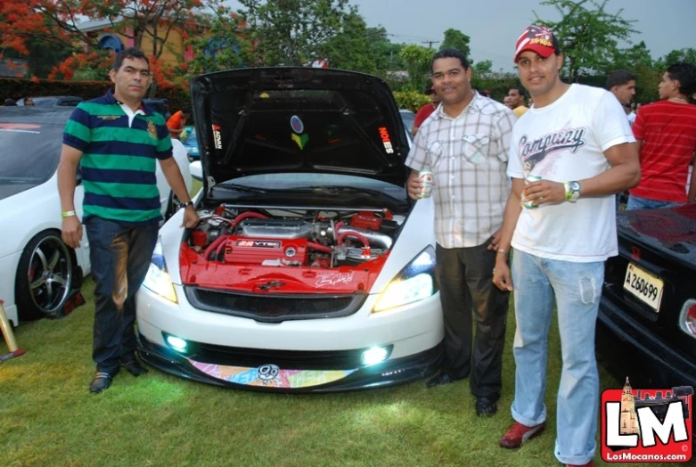 four men standing beside a car with a hood open