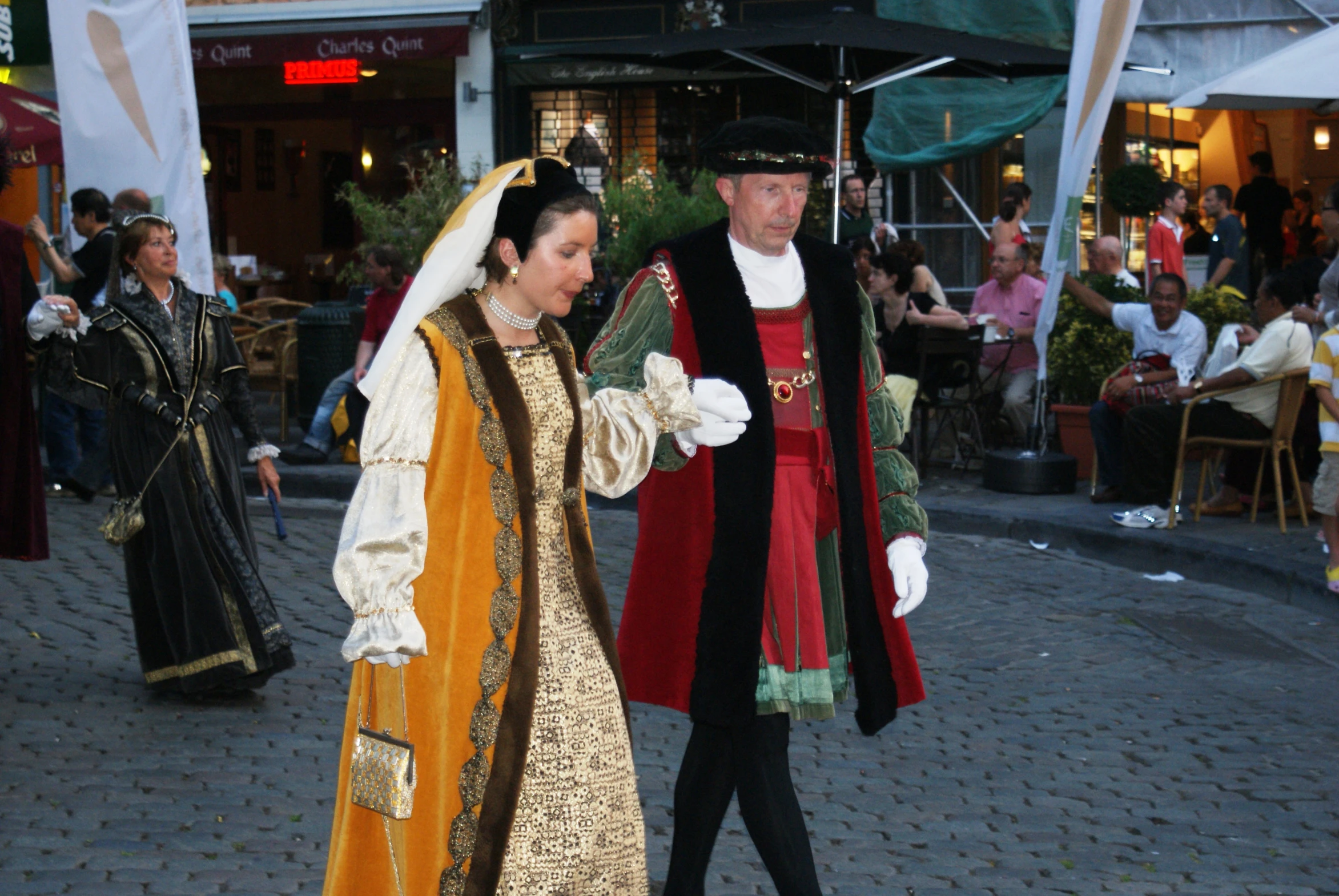 two people dressed in renaissance fashion walking down a street