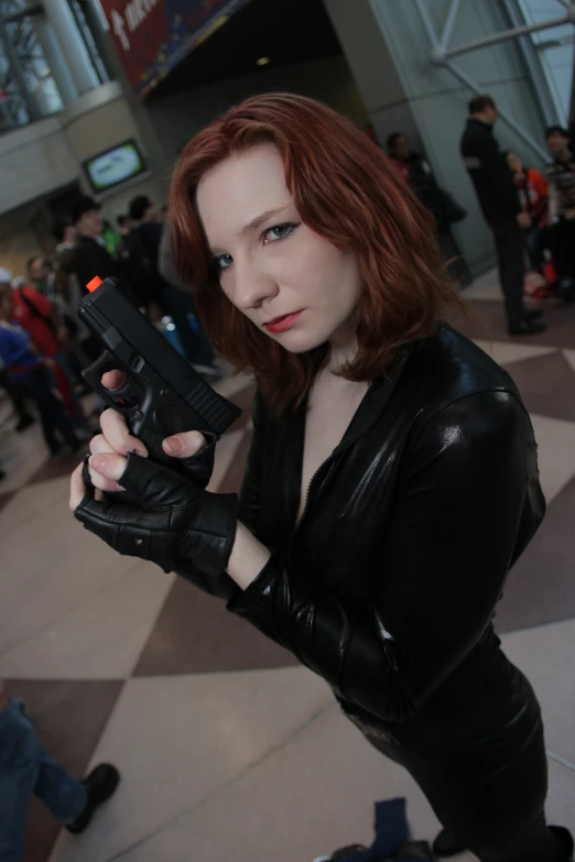 a lady in black with a gun posing for the camera