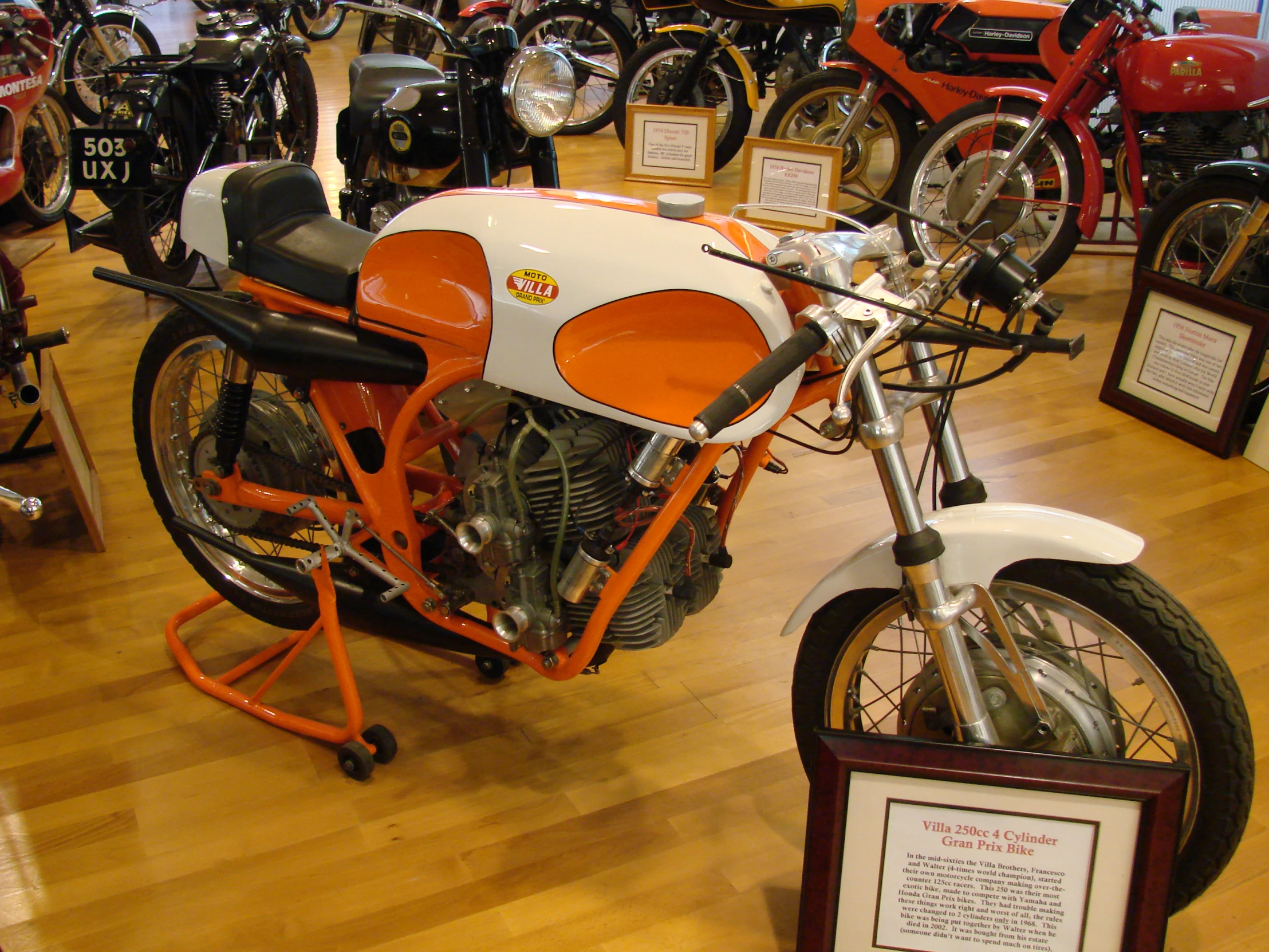 a close up of an orange and white motorcycle on display