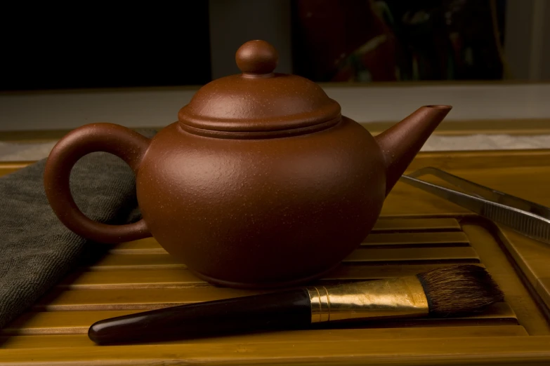 a brown teapot sitting on top of a bamboo table