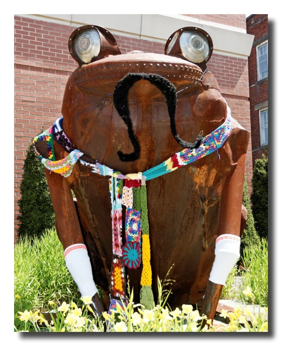 a sculpture with a large brown cow has bright colored necklaces on its chest