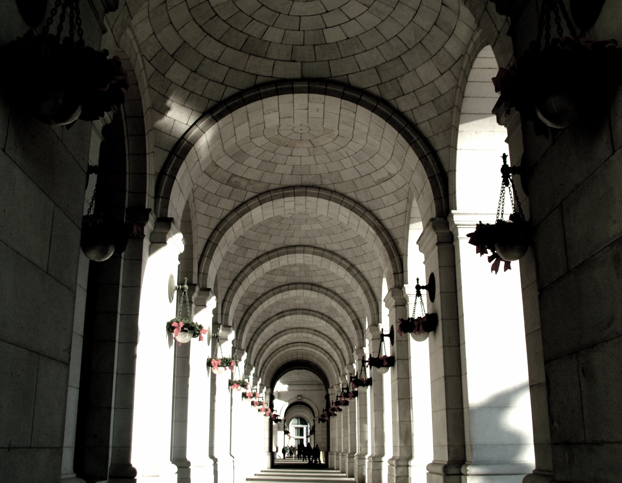 a walkway lined with tall brick arches next to buildings