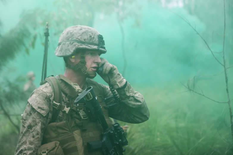 a soldier talking on a phone while holding a gun