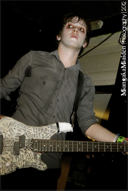 a man with a grey shirt playing a guitar