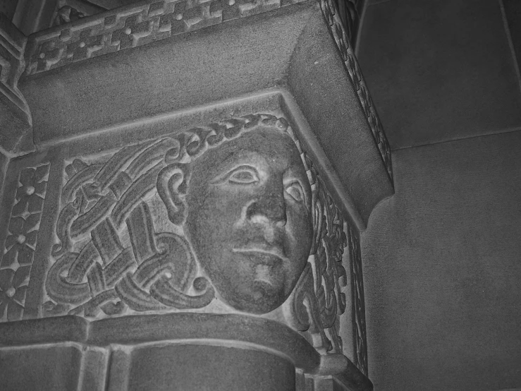 a black and white po of a close up s of a stucco wall with a face drawn on it