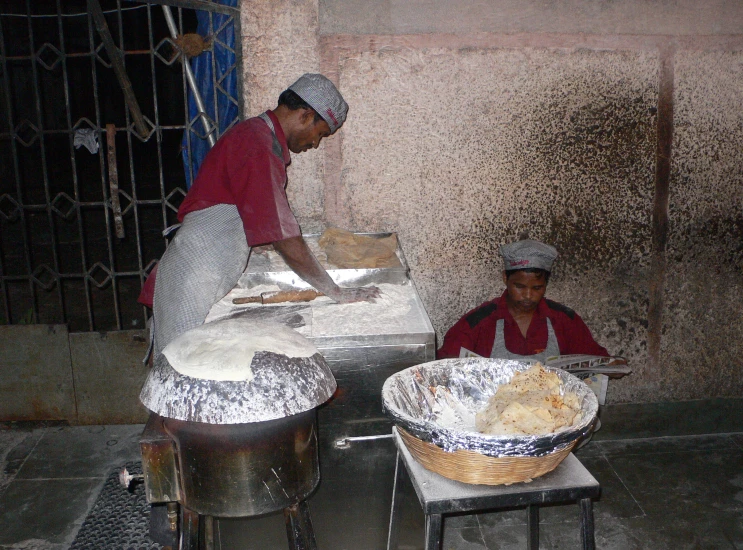 two men working in a kitchen with pots and pans