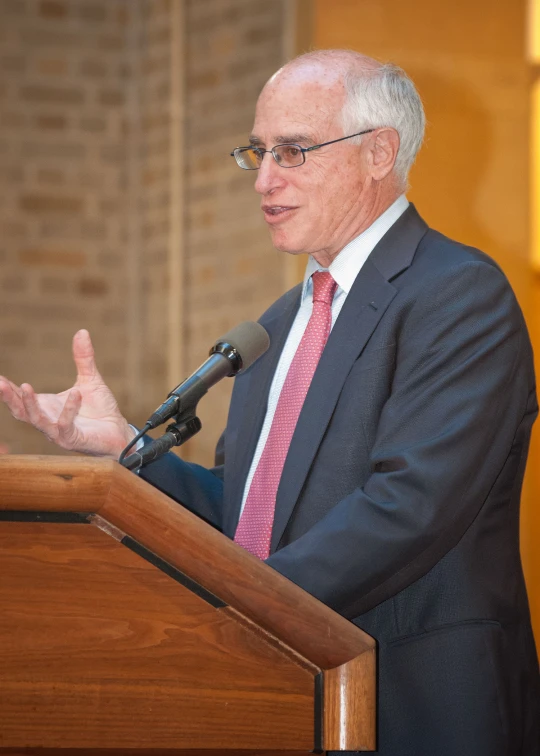 a man wearing a suit speaking from a podium