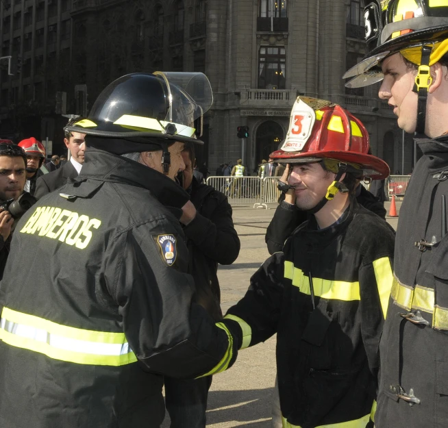 several firefighters standing in the street talking to each other