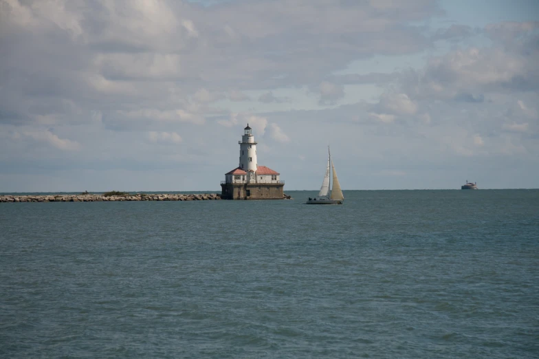a sailboat passes by a lighthouse in the ocean