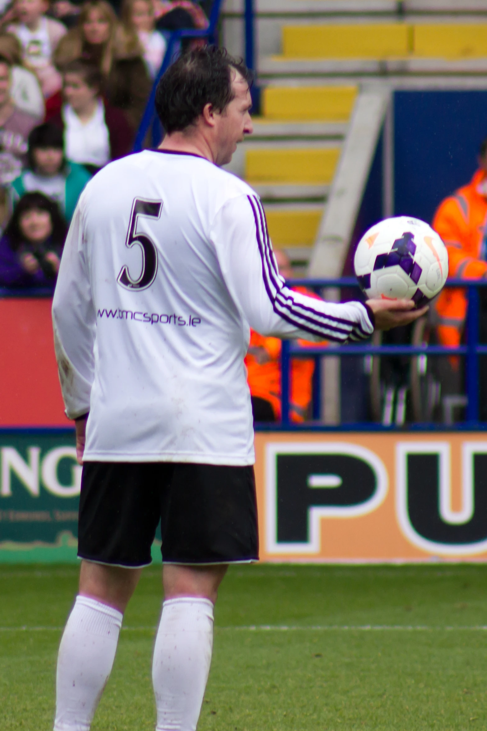 man holding soccer ball standing in the middle of a field