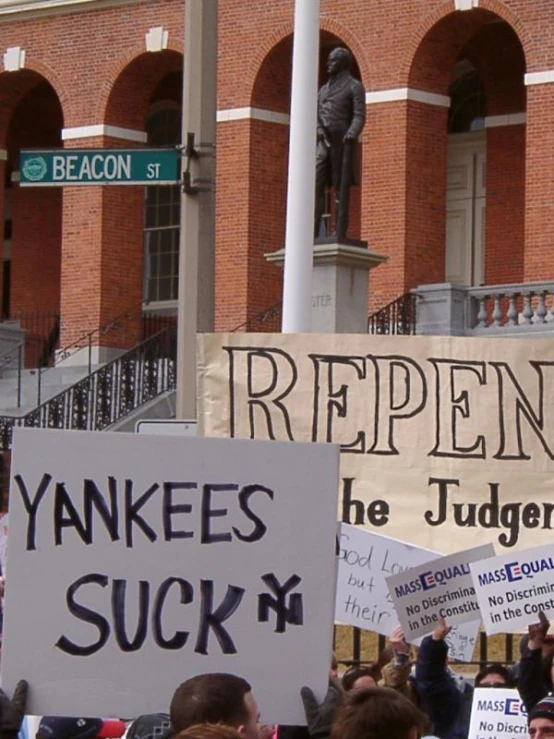 many people holding signs are standing outside