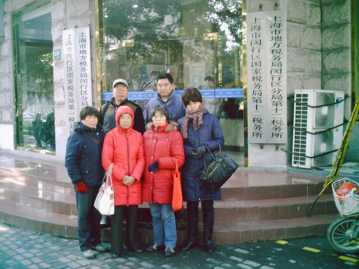 a group of people stand together outside of a chinese store