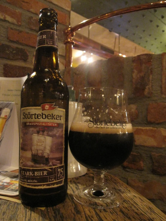 a beer glass sitting next to a bottle on top of a table