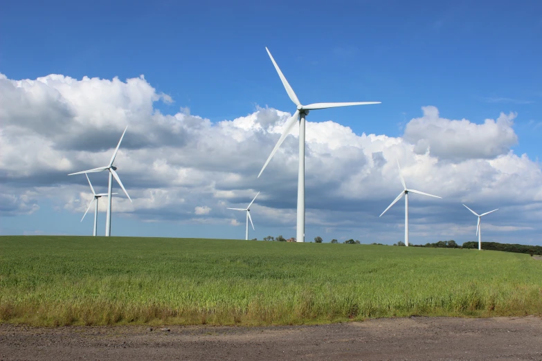 many windmills stand in the field beneath cloudy skies