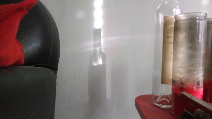 a glass bottle with soing behind it is in a room