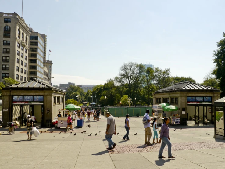 people walking on a plaza next to several gazebos