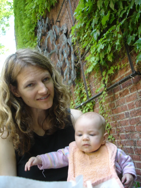 a smiling young woman holds her baby while looking at the camera