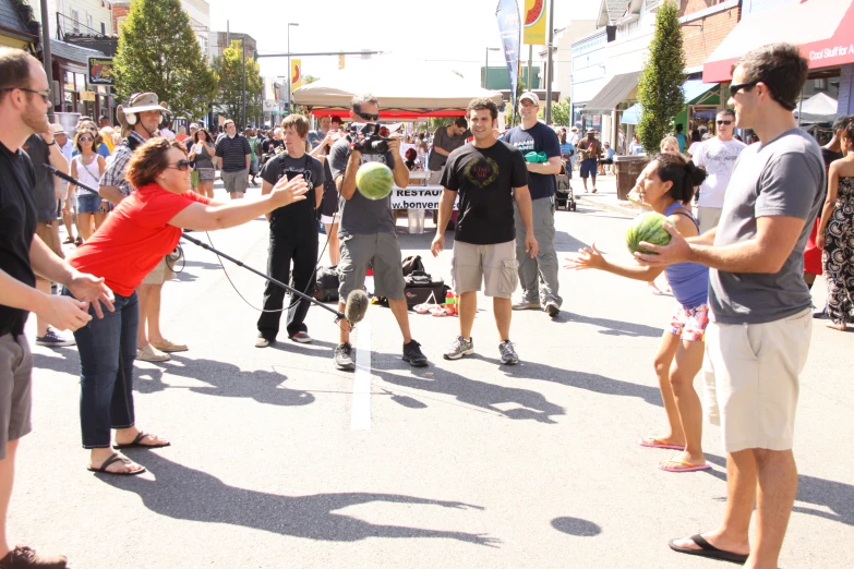 a crowd of people play a game of baseball on a city street