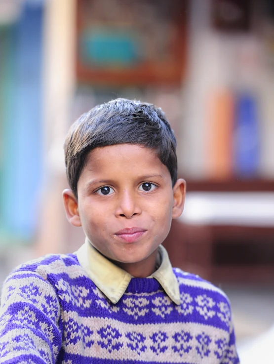 a boy wearing a sweater in a village