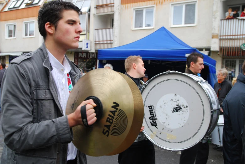 young man holding up drums at outdoor event