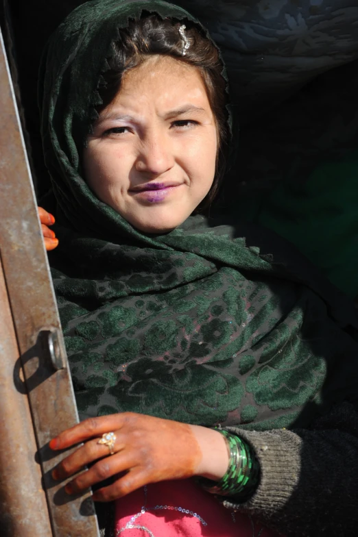 a woman in green and grey holds an open door