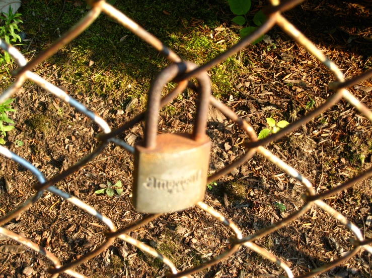 a small padlock is on a chain link fence