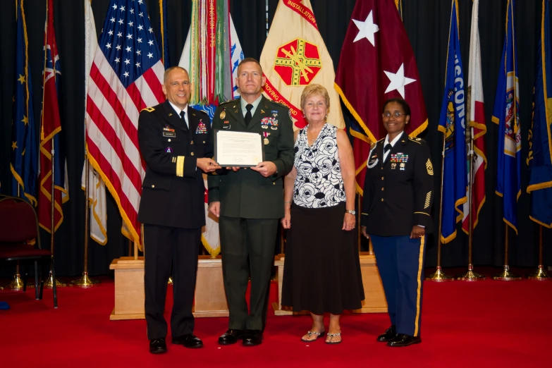 military personnel and woman receive an award on stage