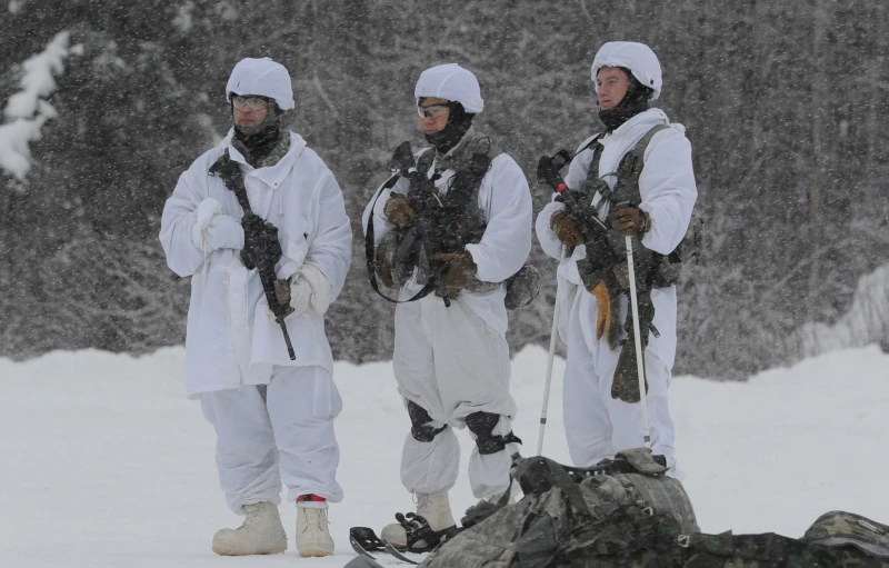 three men dressed in white standing next to a sleeping bag