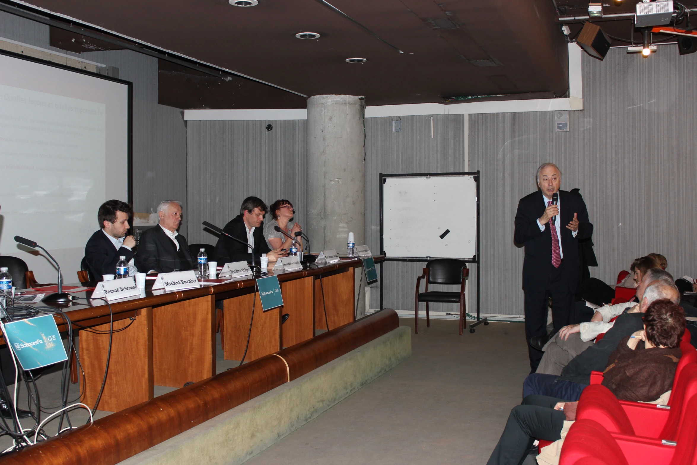 men in suits and ties sit at the long tables with microphones