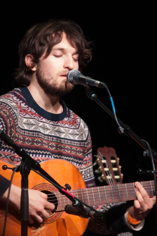 a man with a guitar is playing on stage