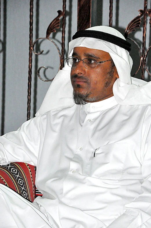 a man wearing a white robe sitting in a chair