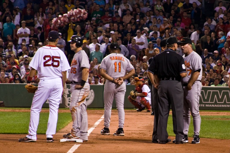 some baseball players are talking while a crowd watches