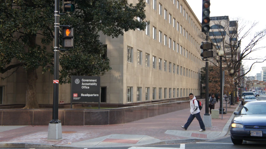 a man crossing the street with a backpack in tow