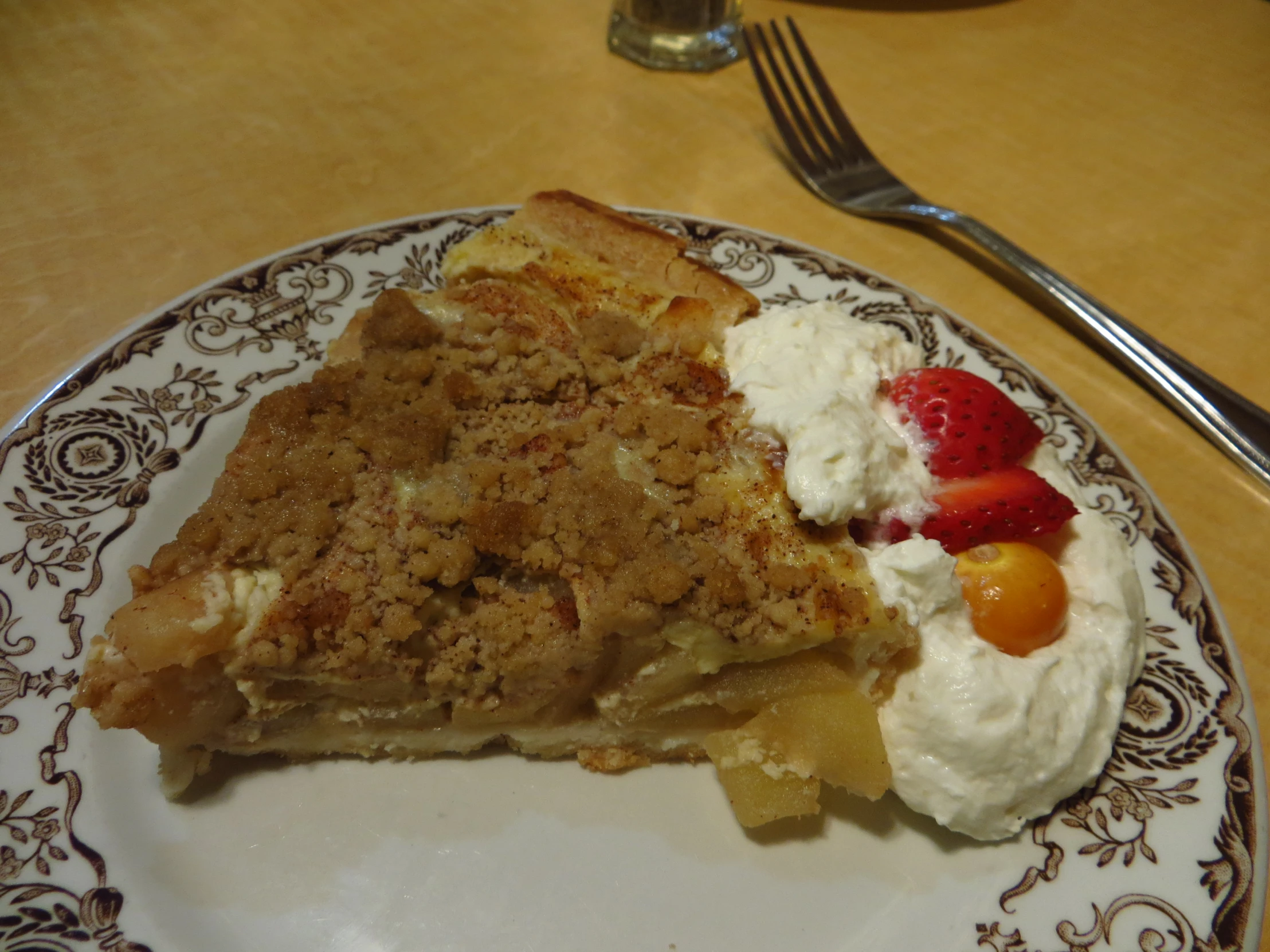 a slice of pie on a plate topped with whipped cream and fruit