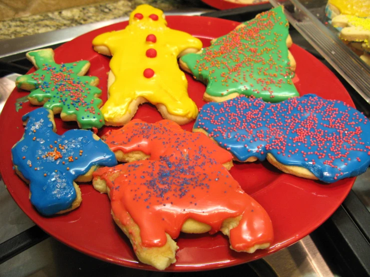 four decorated cookies on a red plate in the shape of star