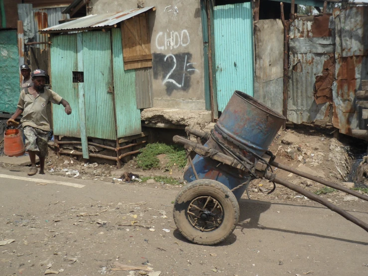 a rusty wheel laying on the ground next to a shack