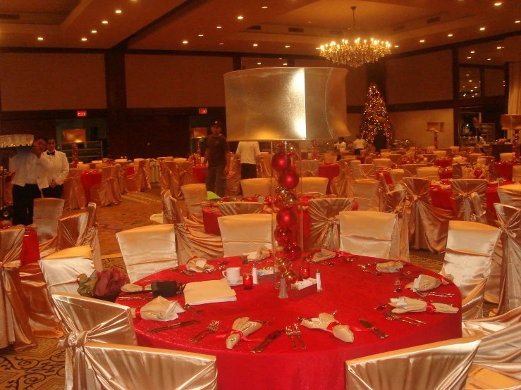 several tables covered in silver and red linens with decorations on them