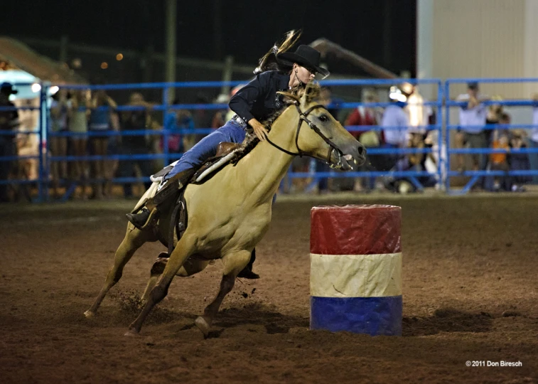 a person is riding a horse around a small barrel