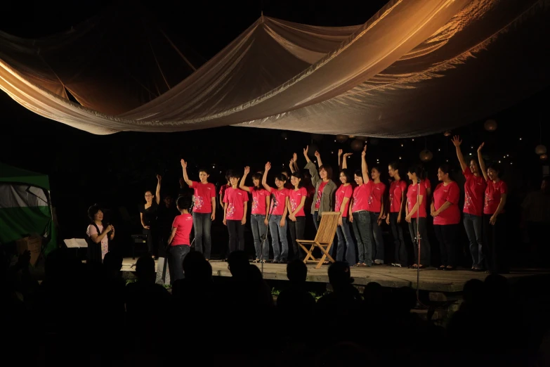 a choir performs on stage in red shirts