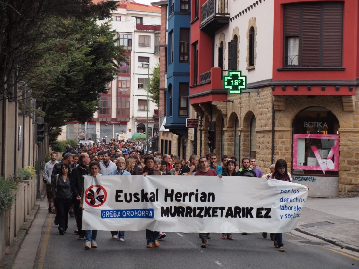 group of people walking in the street with banner