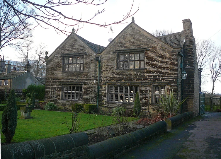 an old brick house with some shrubs growing around