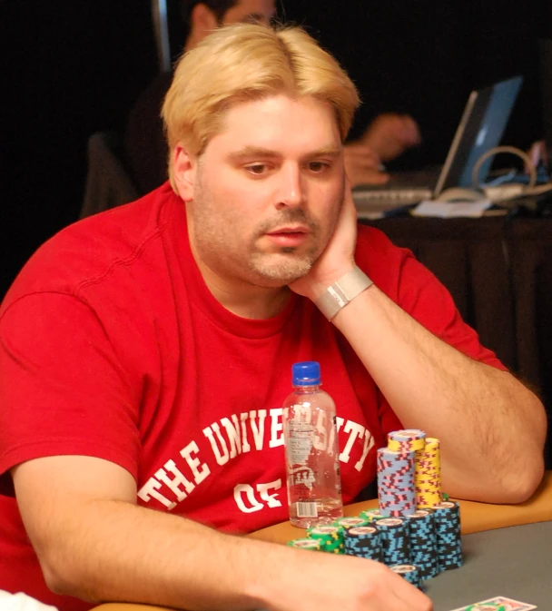 a man in a red shirt at a poker table with lots of chips