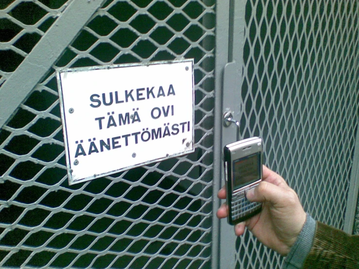 a person holding an old cell phone in front of a fence