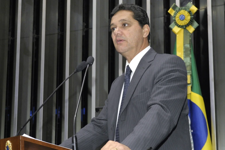 man standing in front of a podium and a flag behind him