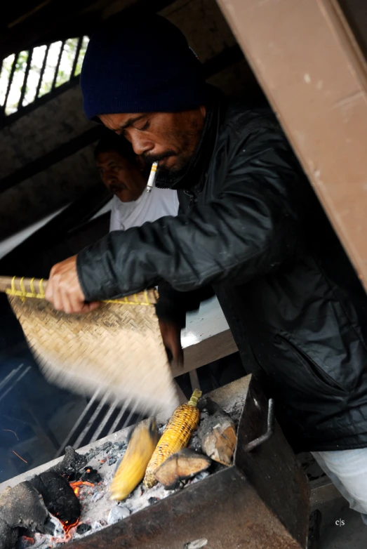 a man preparing food in a large wooden grill